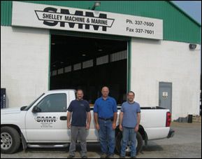 Three men in front of Shelley Machine & Marine store